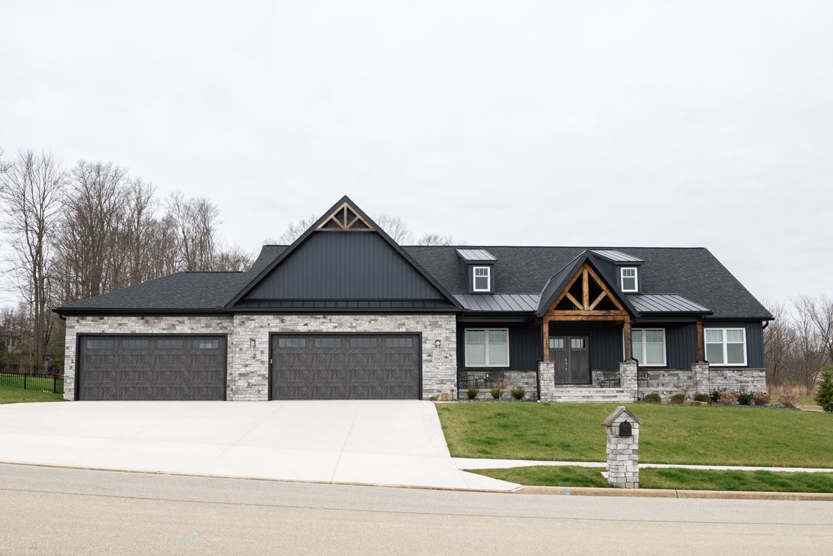 A large house with three garage doors is sitting on top of a hill.