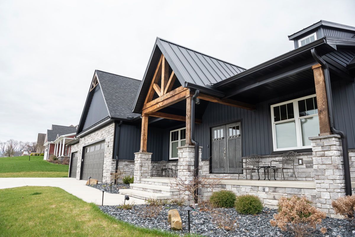 A large black house with a metal roof and a porch.