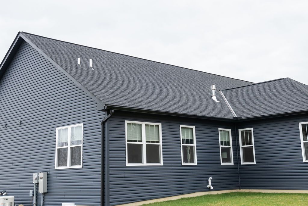 A black house with a gray roof and a lot of windows.