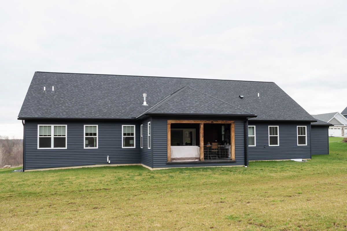 The back of a house with a porch and a lot of windows.
