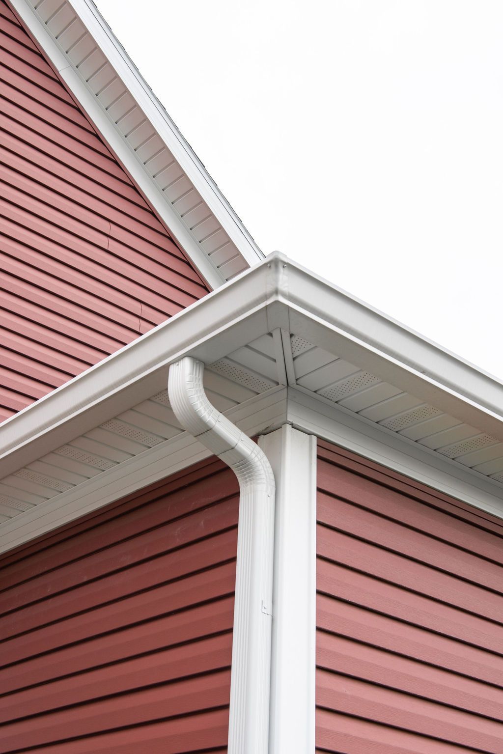 A red house with a white gutter on the side