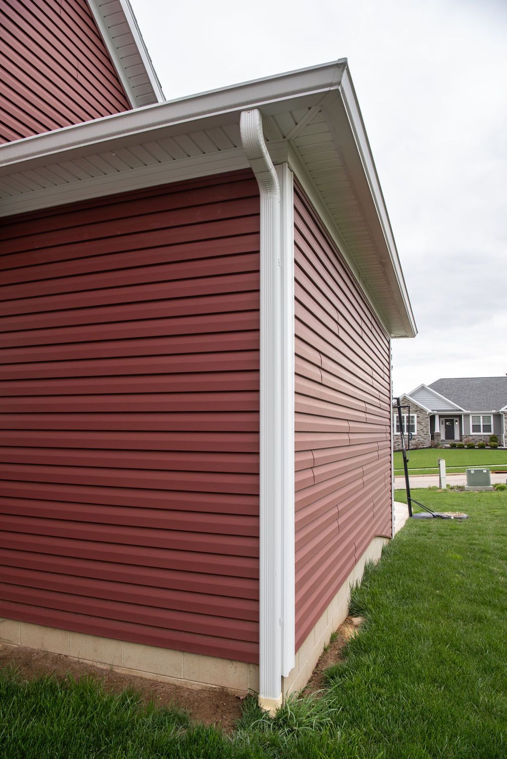 A red house with a white gutter on the side of it.