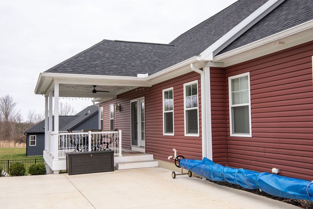 A red house with a blue tarp on the porch.