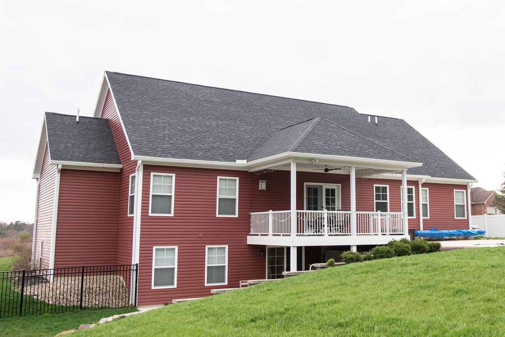 A large house with red siding and a black roof