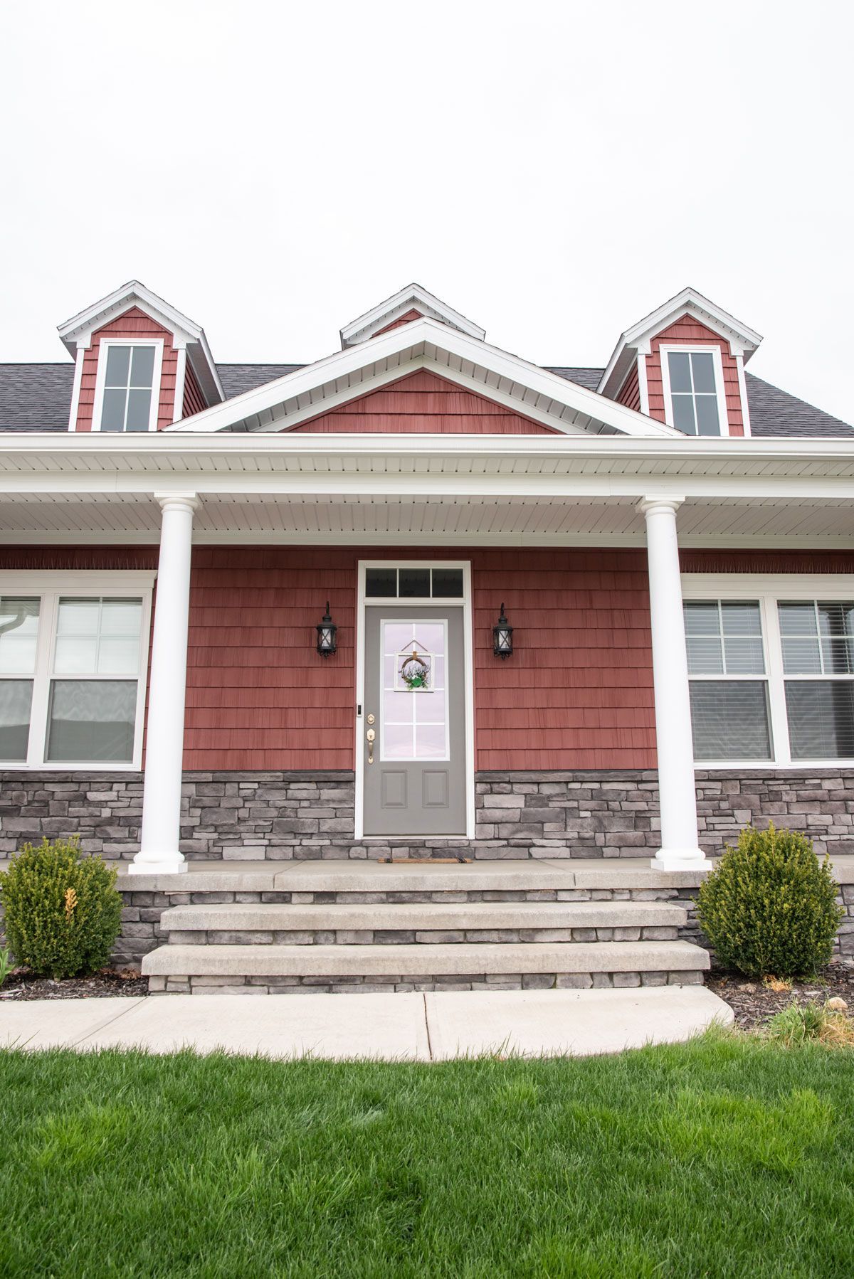 The front of a red house with a porch and steps.