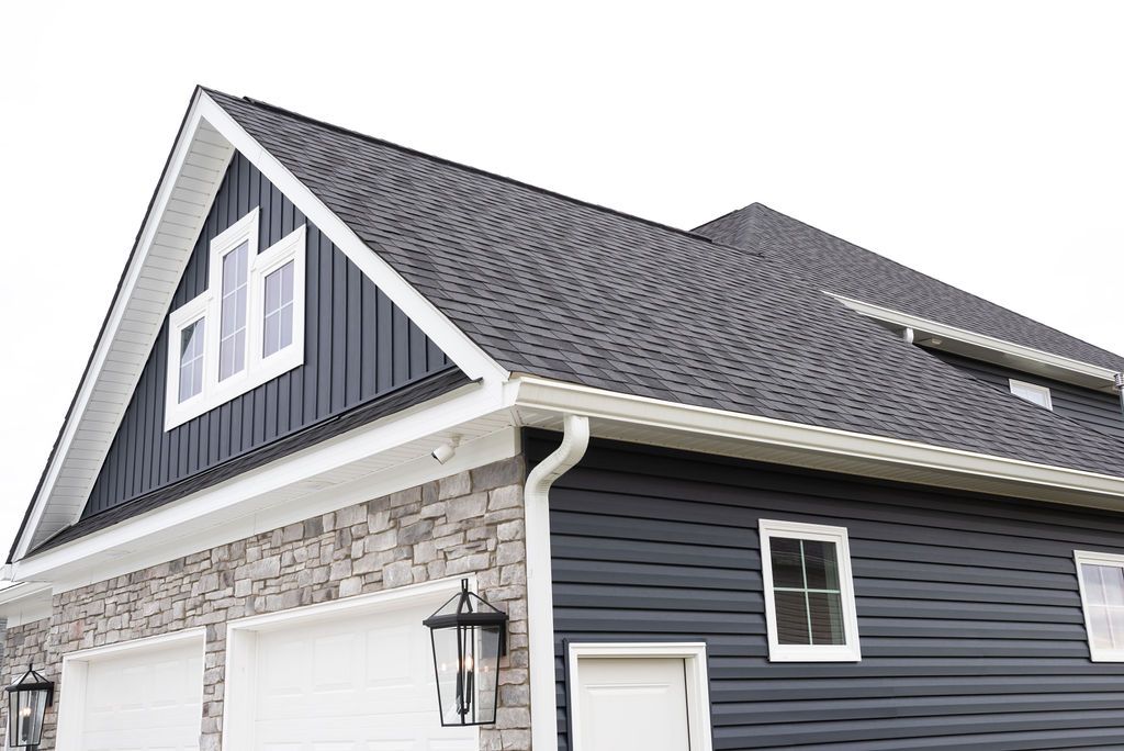 A black and white house with a gray roof and two garage doors.