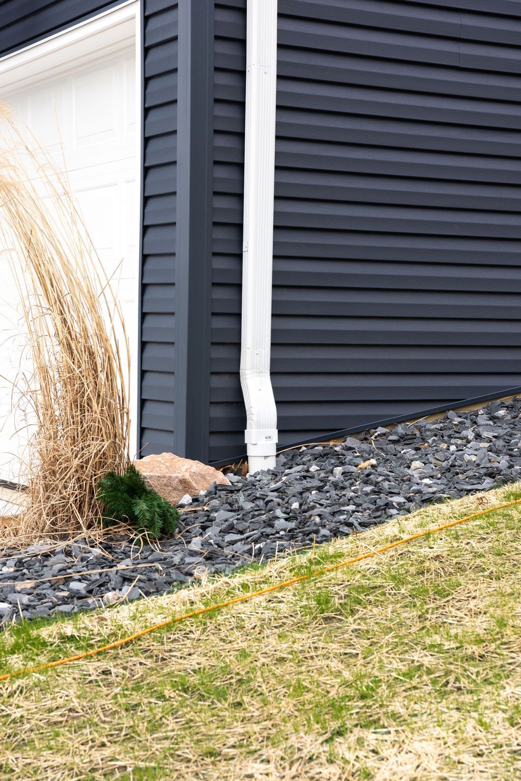 A black house with a white garage door and a white gutter.