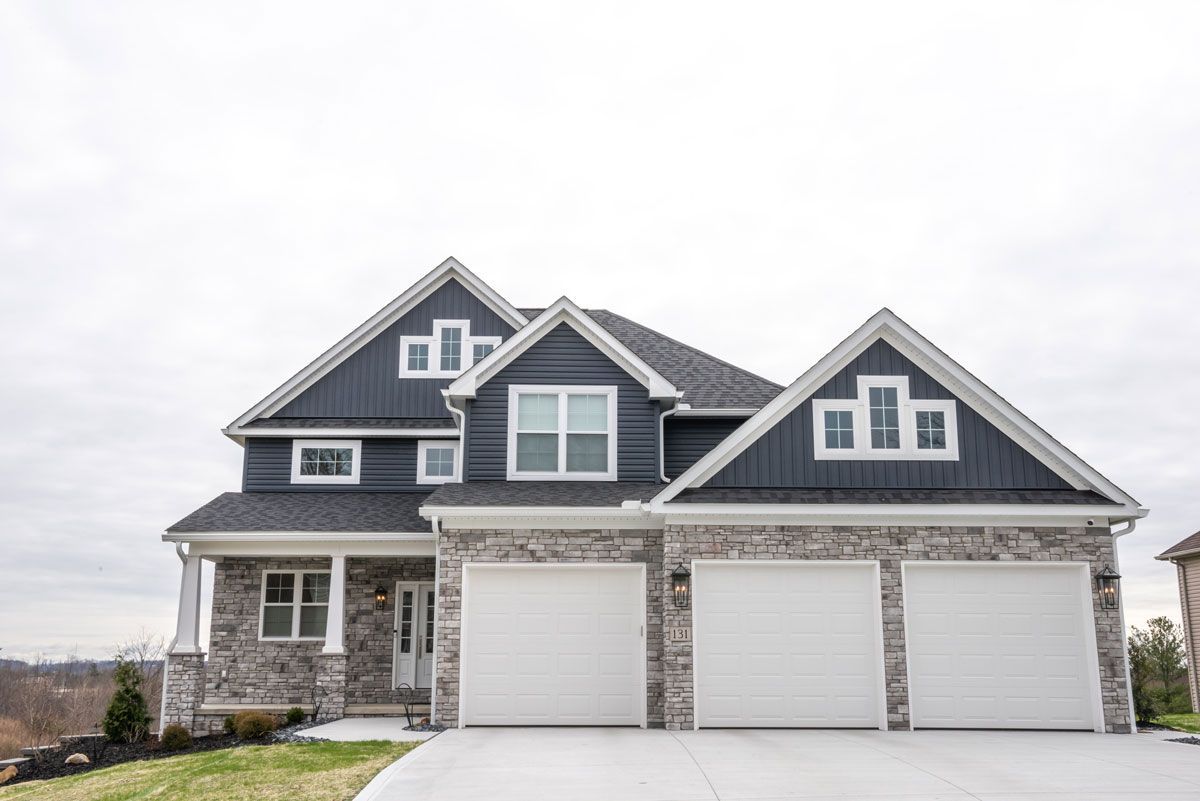 A large house with three garage doors and a gray roof.