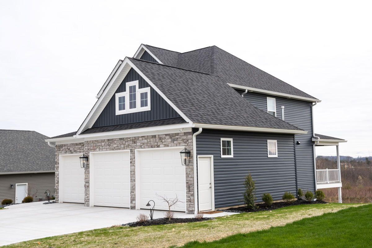 A large house with a garage and a gray roof.