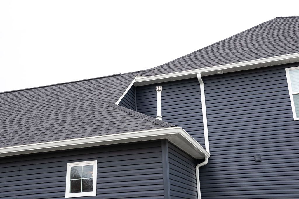 A black house with a gray roof and white windows.
