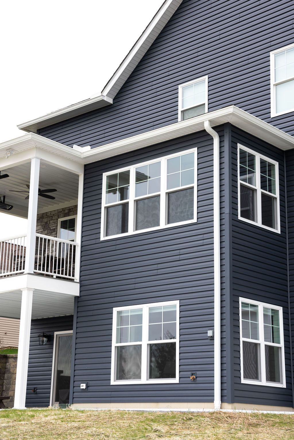 A large blue house with white windows and a balcony.