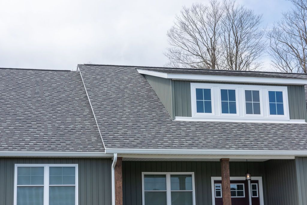 The front of a house with a gray roof and white windows.