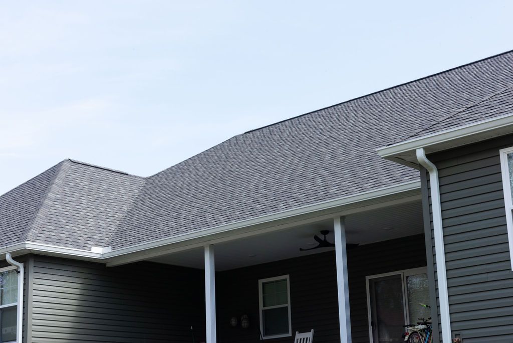 A black house with a porch and a gray roof