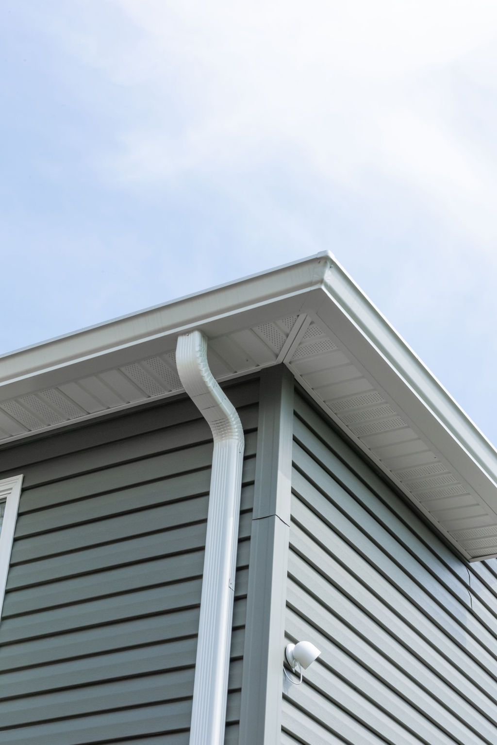 A gray house with a white gutter on the side of it.