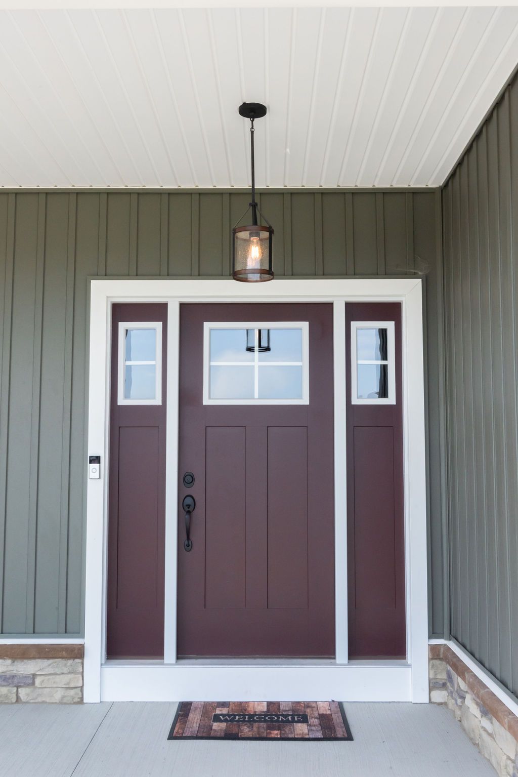 The front door of a house with a red door and a welcome mat.