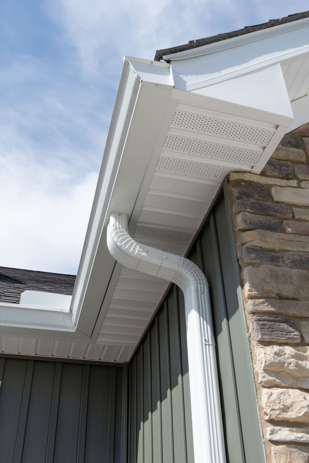 A white gutter is attached to the side of a house.
