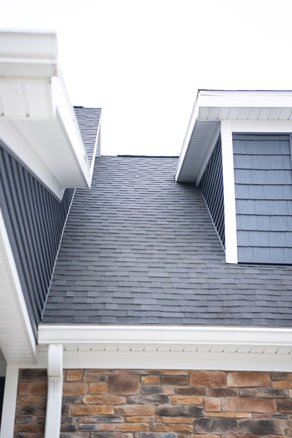 A close up of a roof of a house with a brick wall.