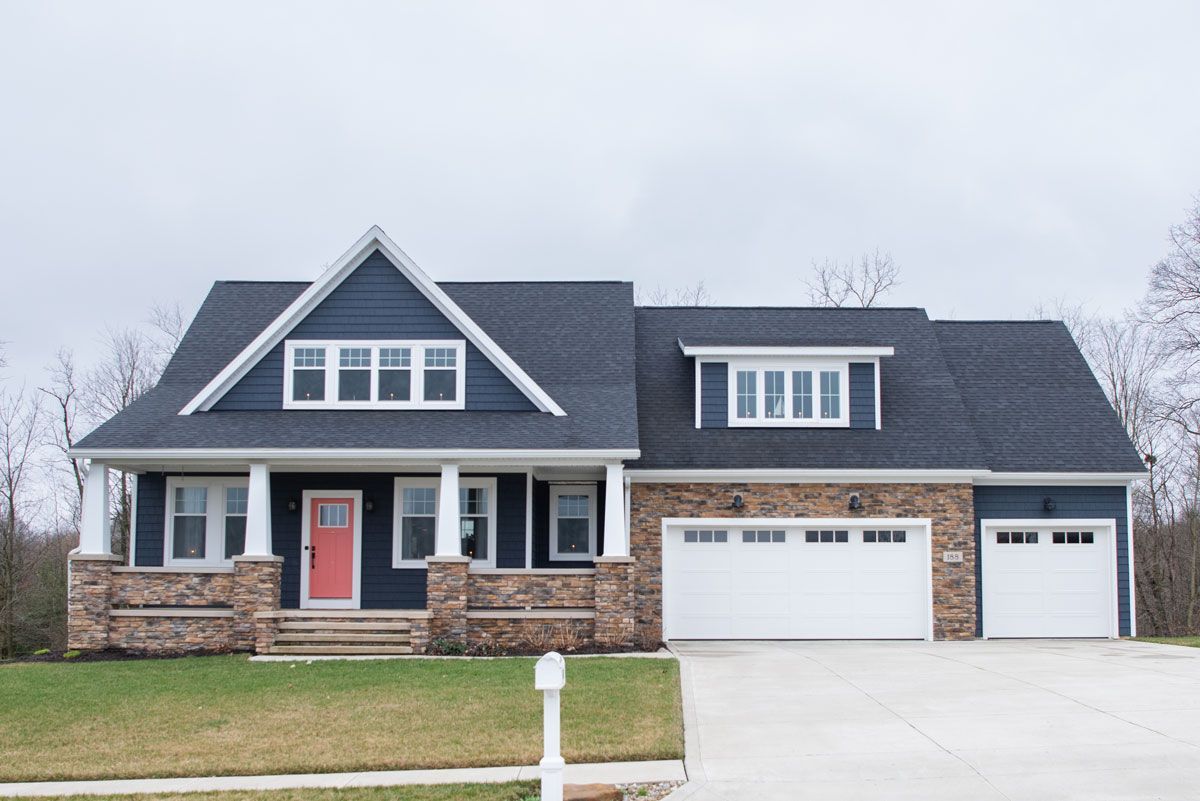 A blue house with a white garage door and a red door