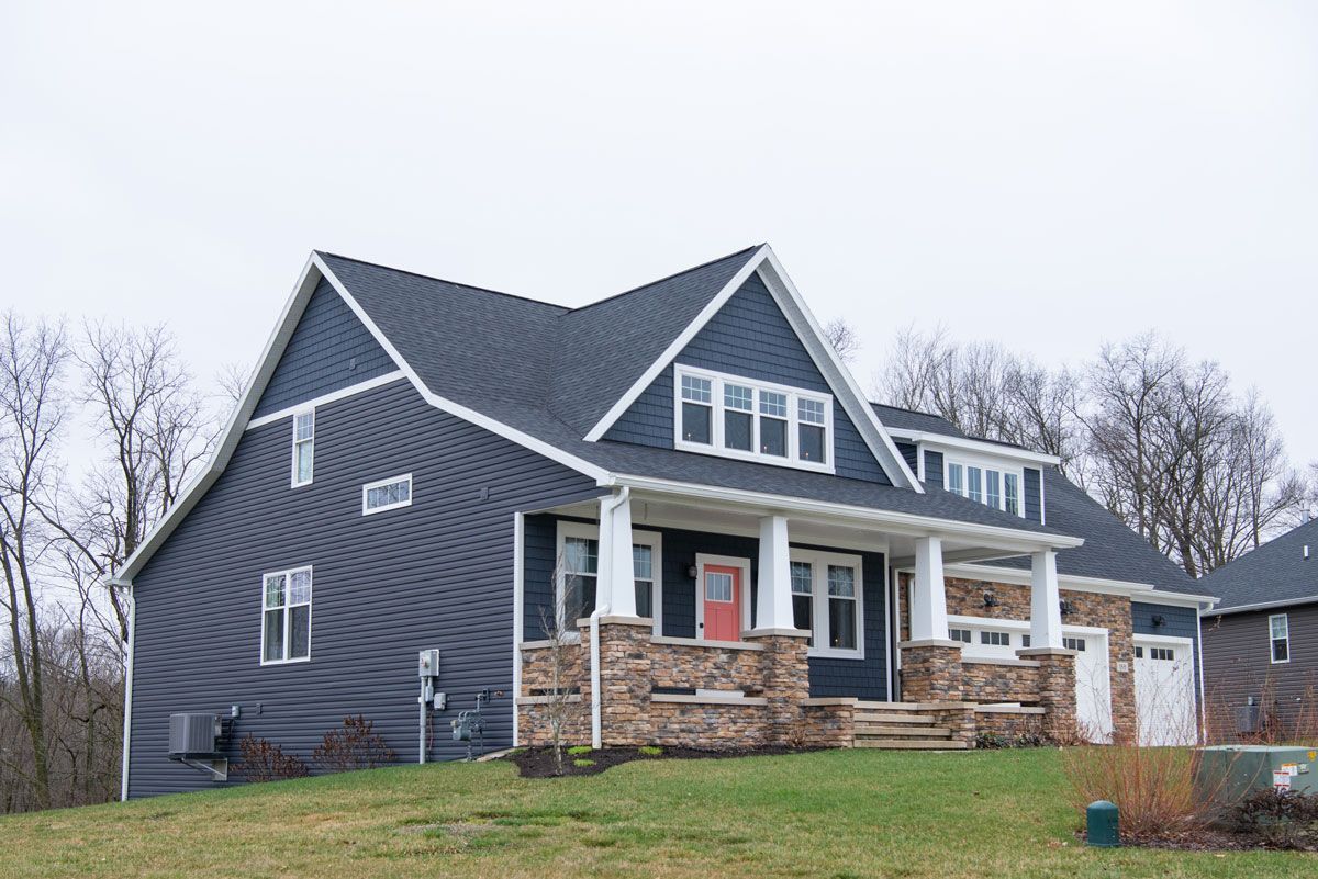 A large house with a red door is sitting on top of a grassy hill.