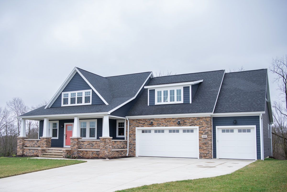 A large house with a blue roof and white garage doors.