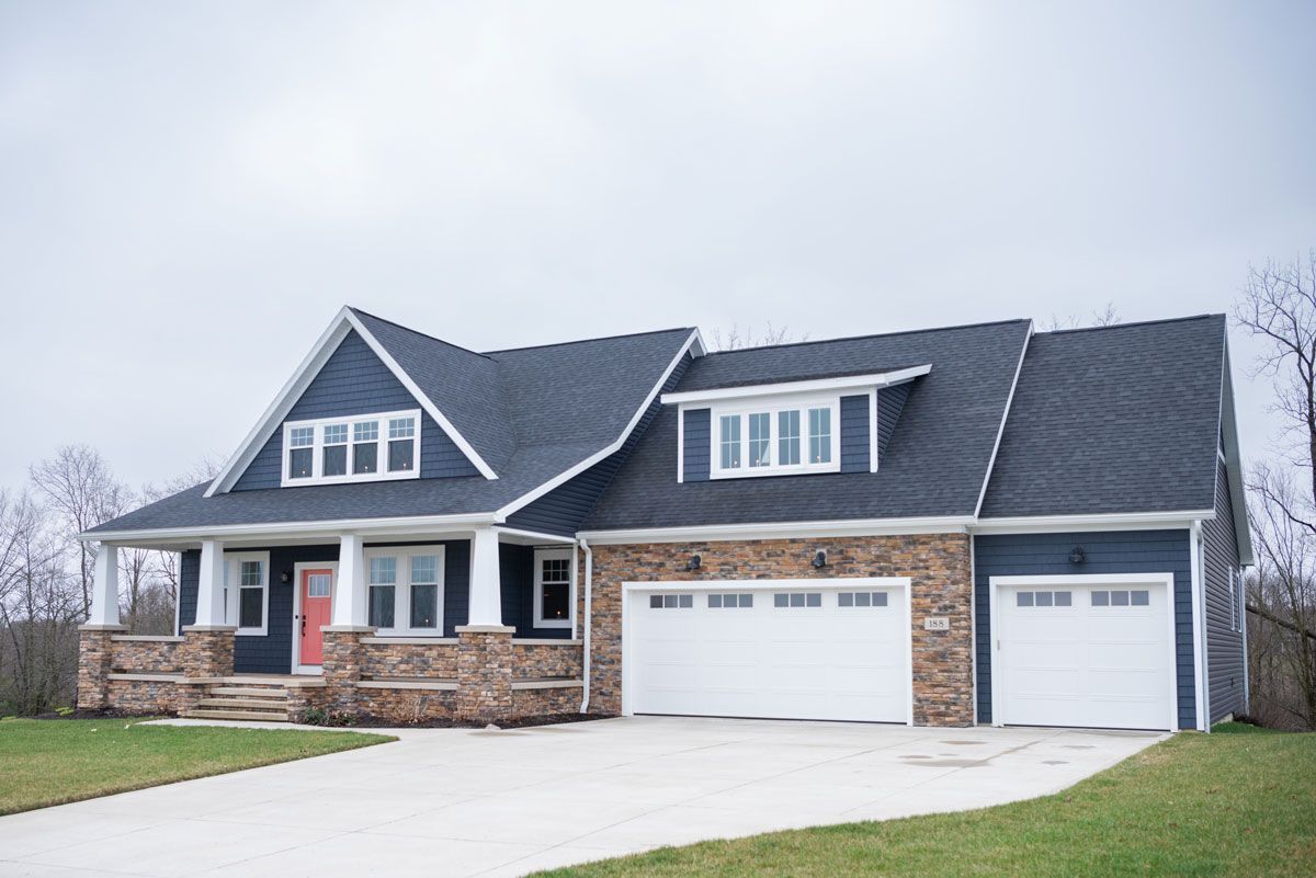 A large house with a blue roof and white garage doors.