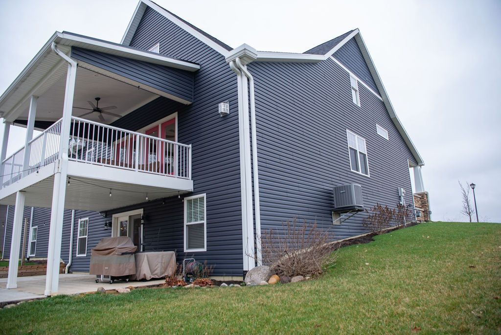 A large house with a balcony and a large lawn in front of it.