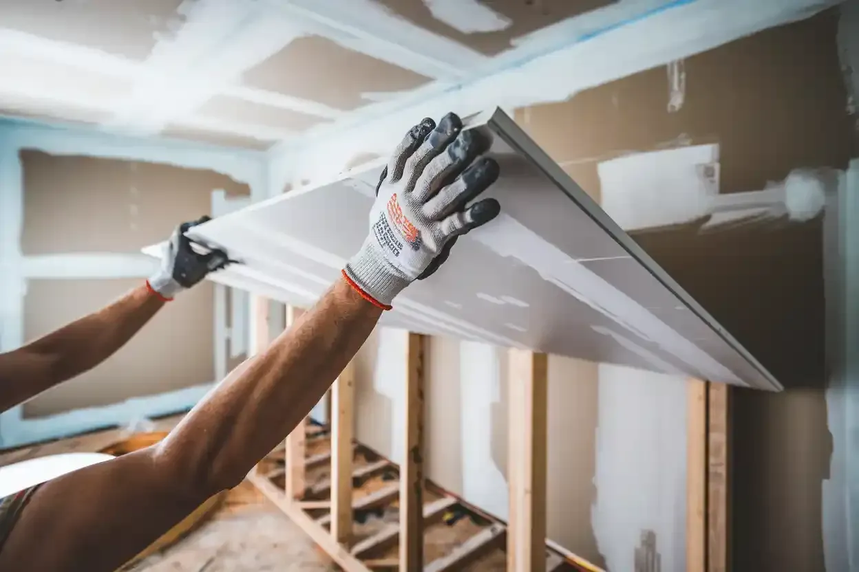 A person is holding a piece of drywall in their hands.