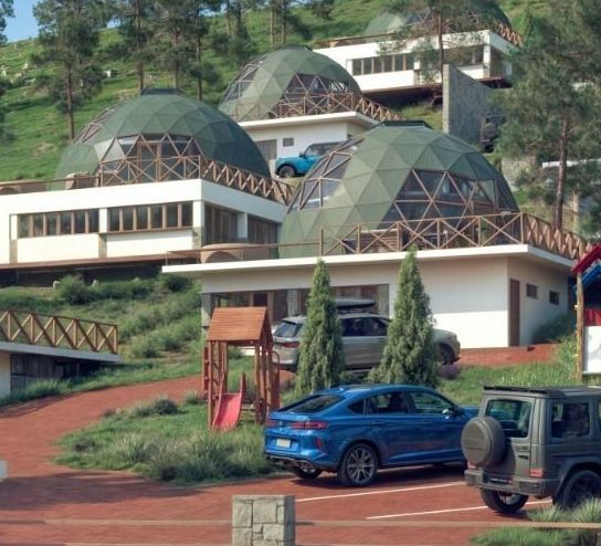 Un coche azul está aparcado delante de un edificio con forma de cúpula.