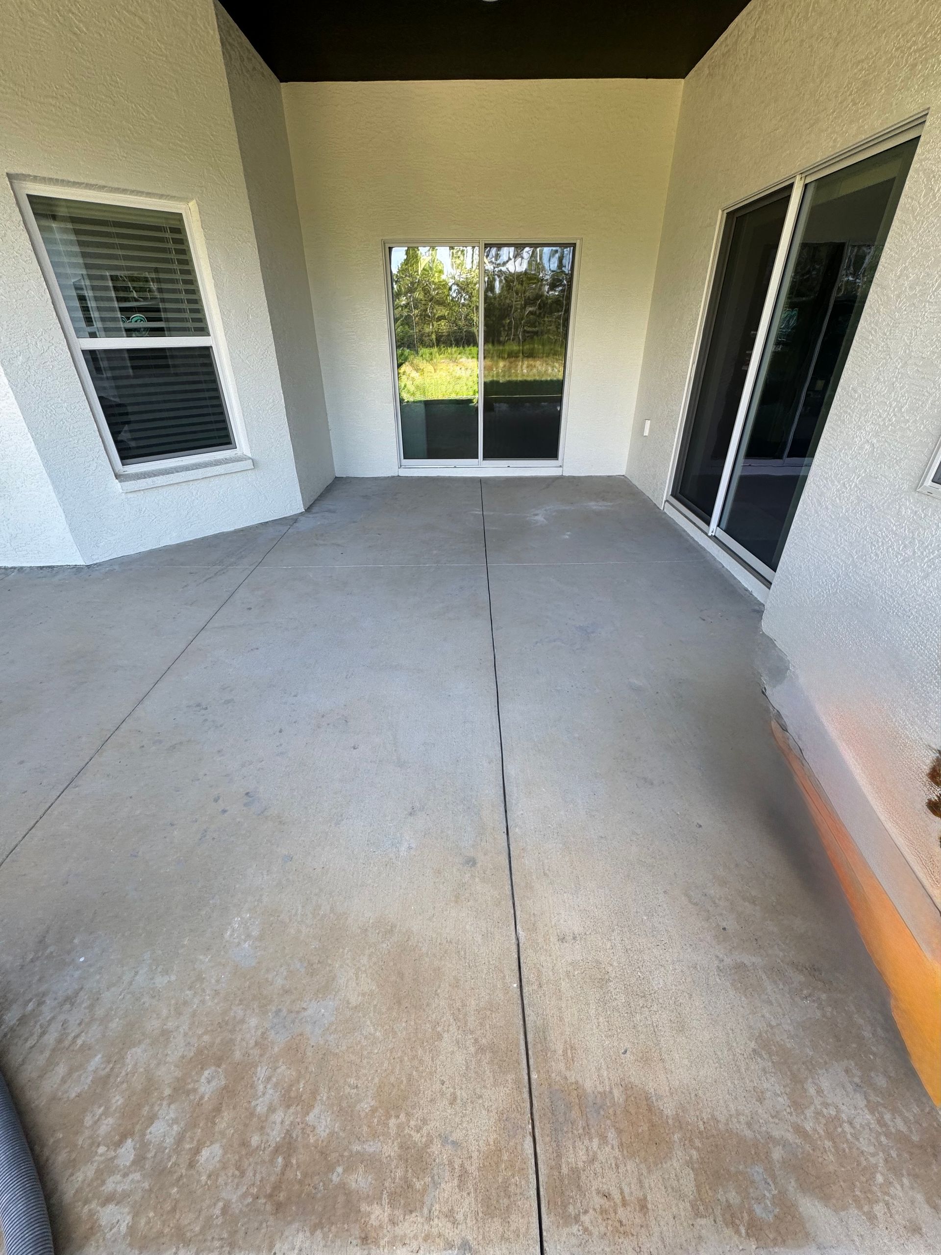 An empty patio with sliding glass doors and a tire on the ground.