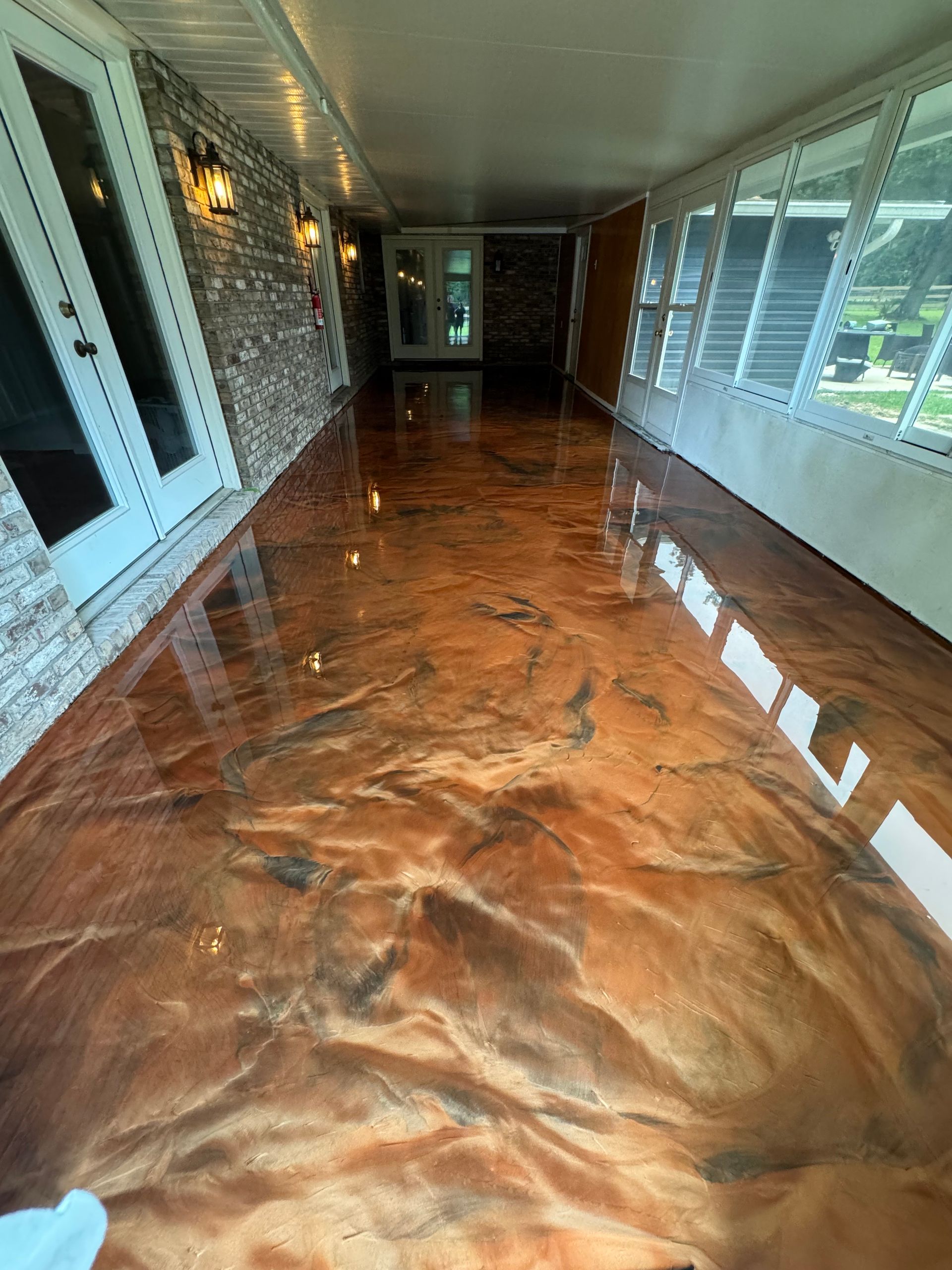 A hallway with a shiny metallic floor and a brick wall.