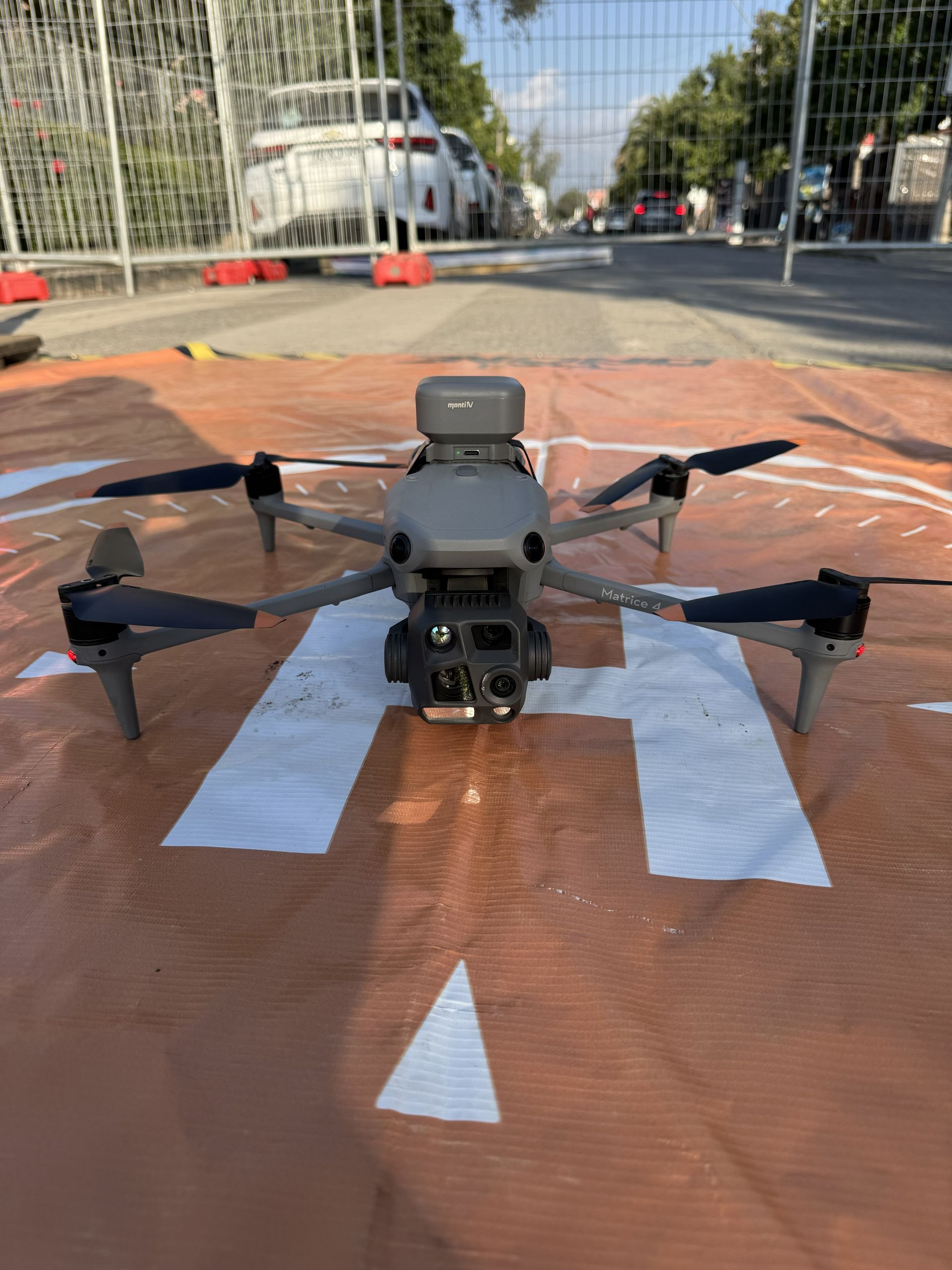 Un dron gris con hélices giratorias contra un cielo azul claro.
