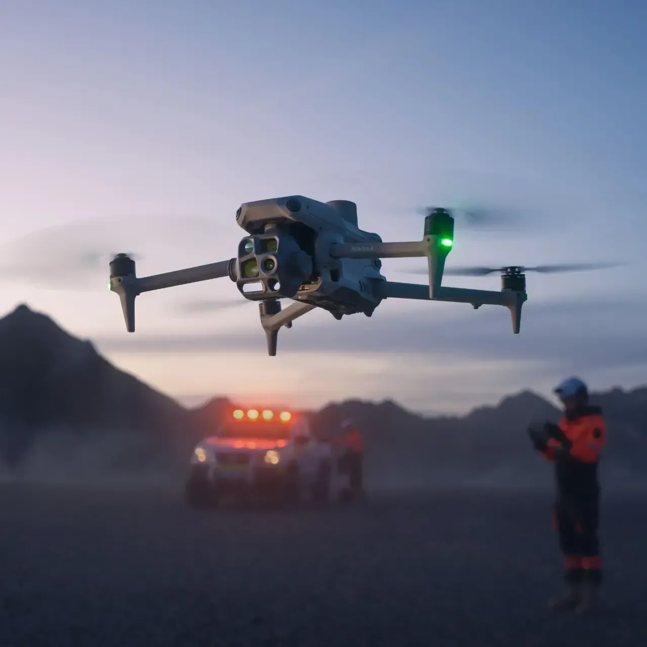 Dron gris en el suelo en una zona cubierta de hierba con sus hélices y patas extendidas.