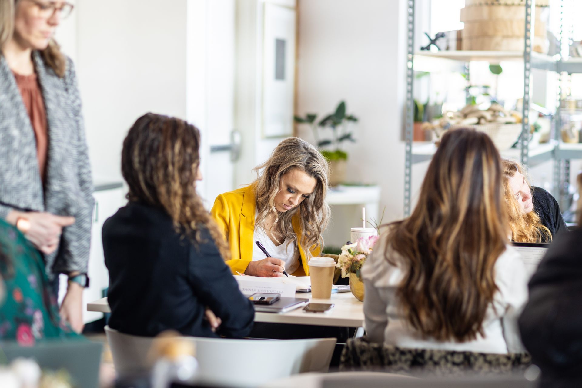 A group of women are sitting at a table having a meeting.