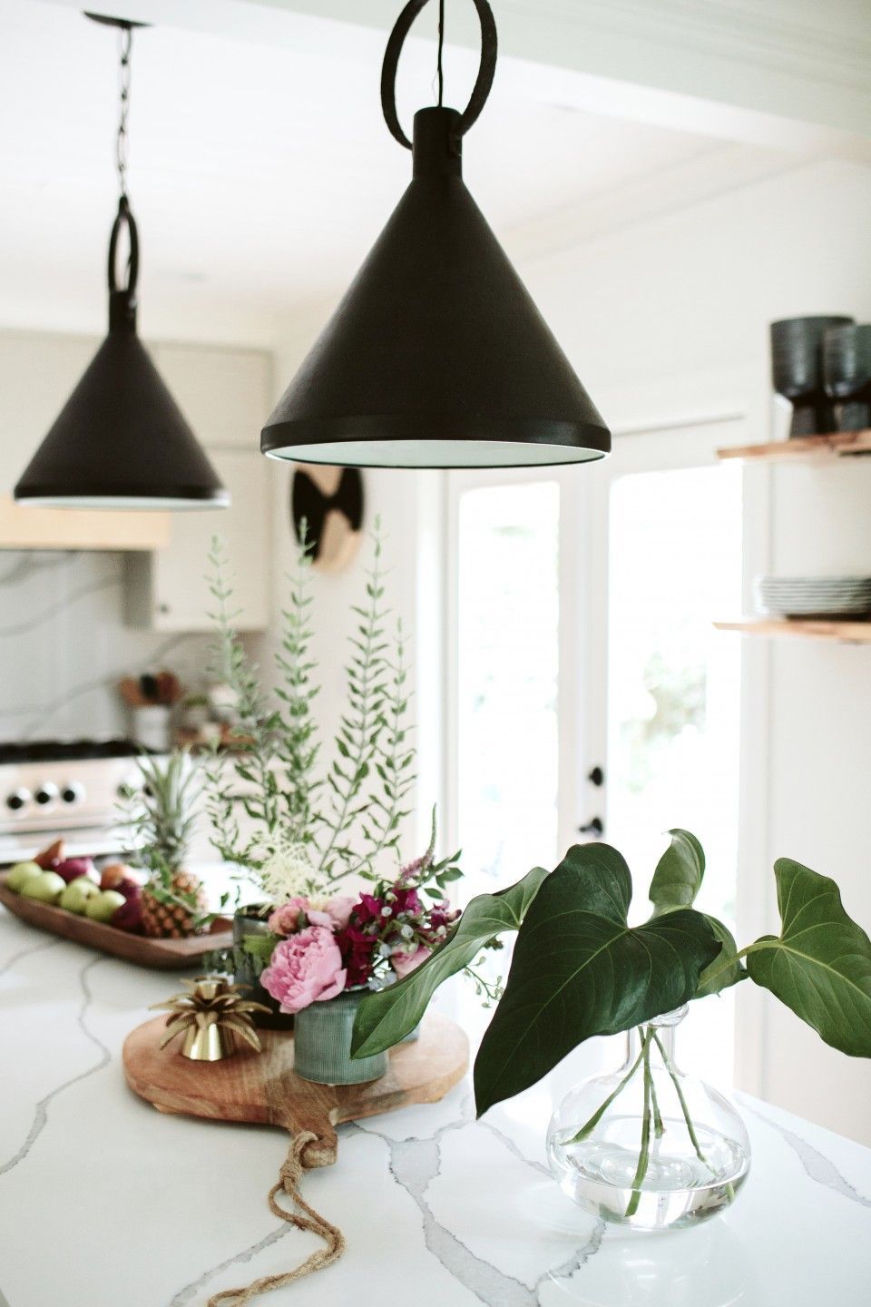 There is a vase of flowers on the counter in the kitchen.