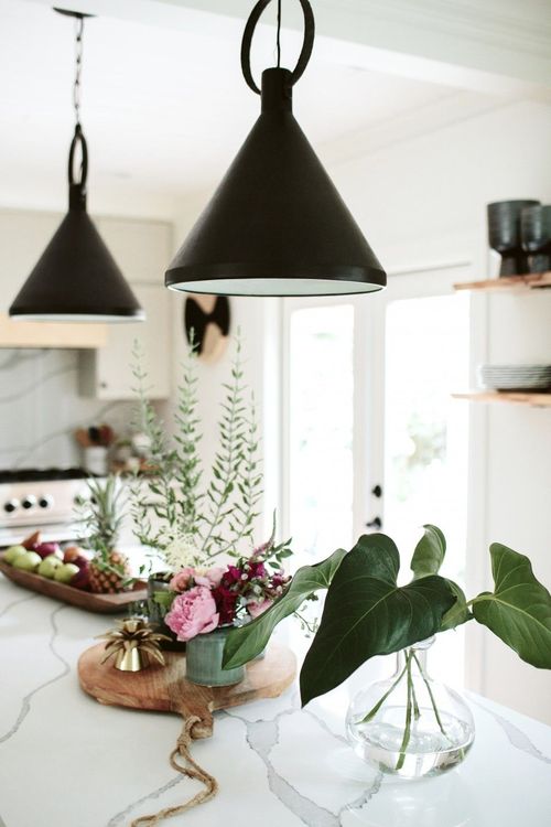 There is a vase of flowers on the counter in the kitchen.