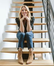 A woman is sitting on a set of wooden stairs.