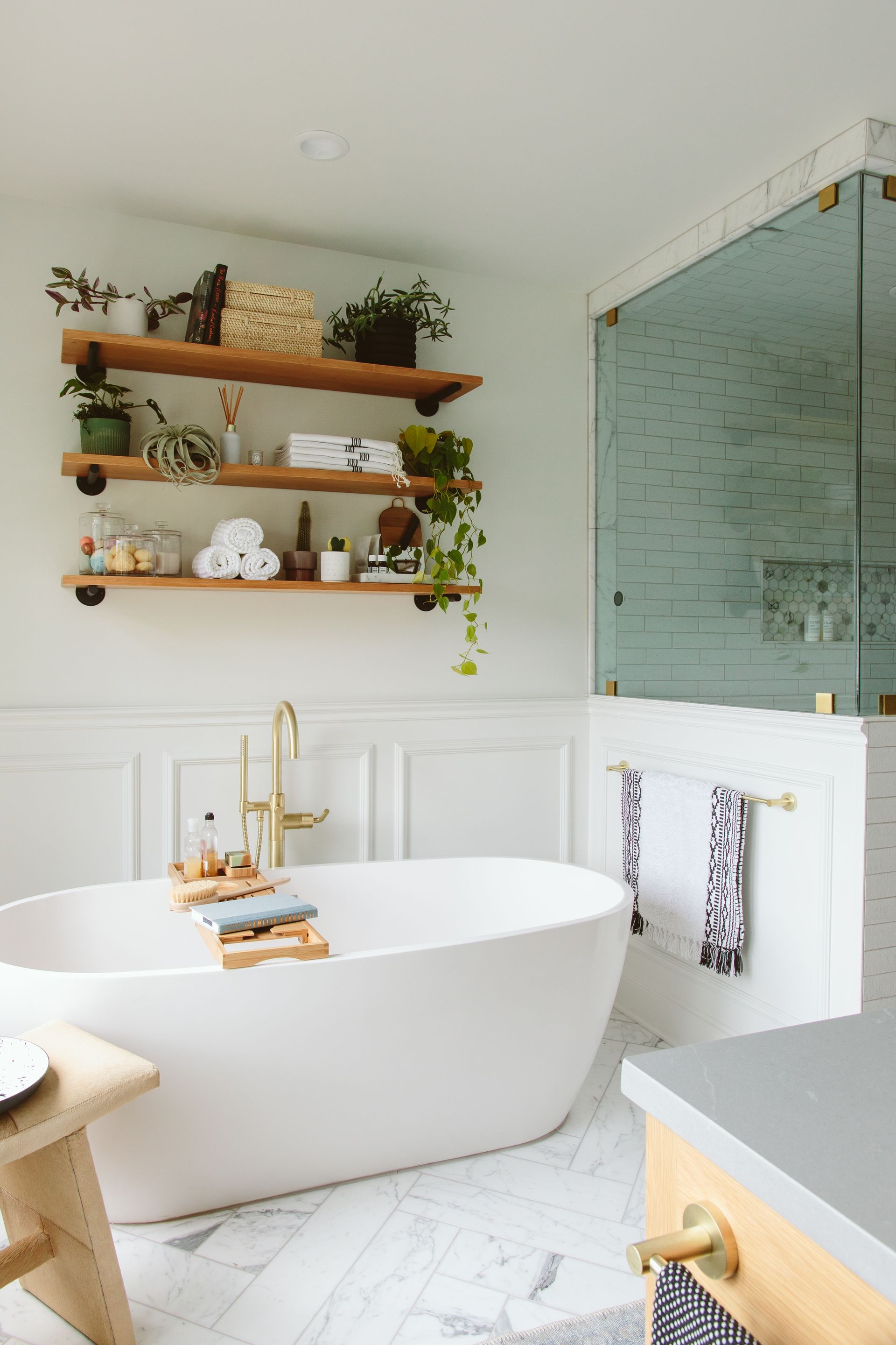 A bathroom with a bathtub , shelves , and a walk in shower.