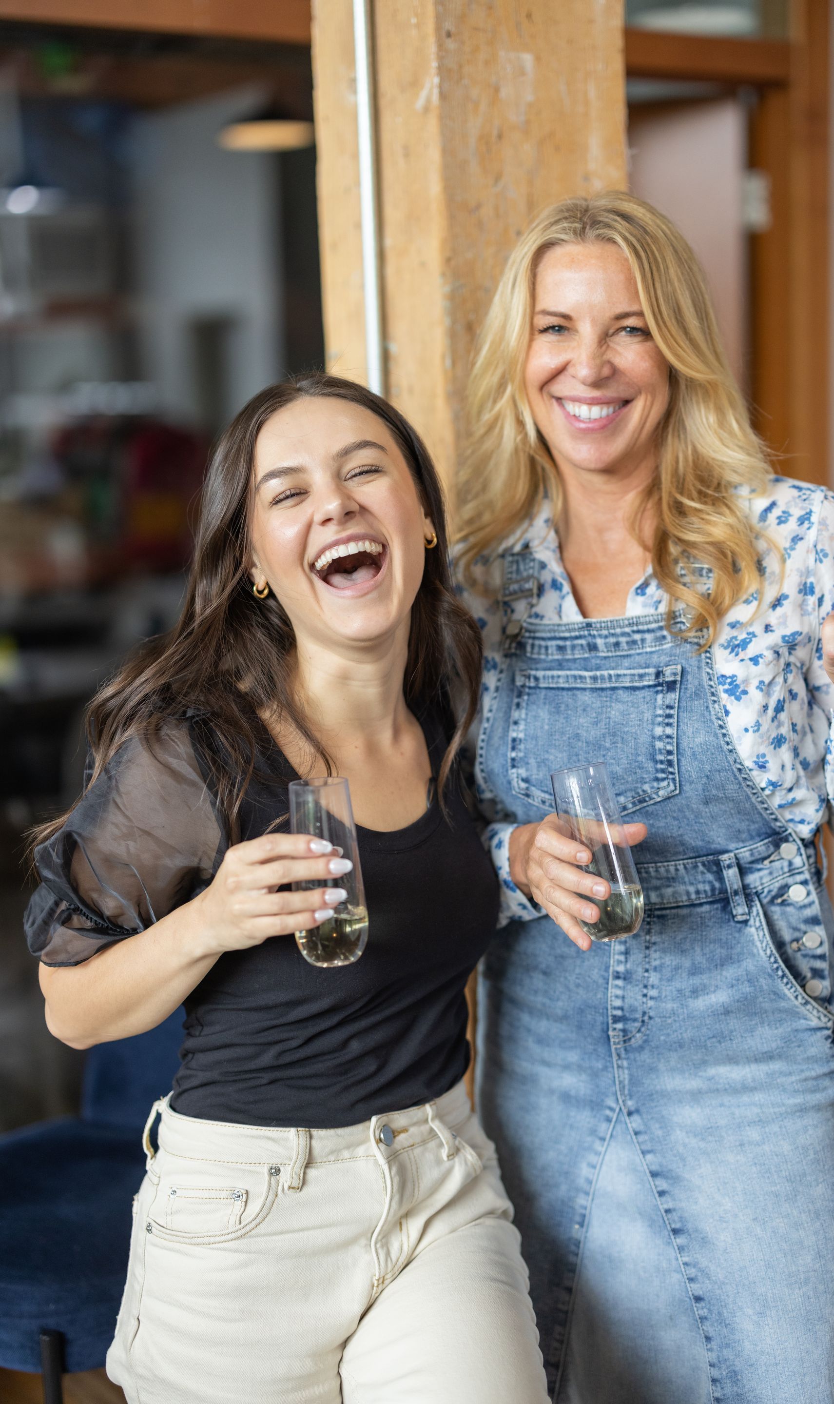 Two women are holding wine glasses in front of a sign that says psychologie of home.