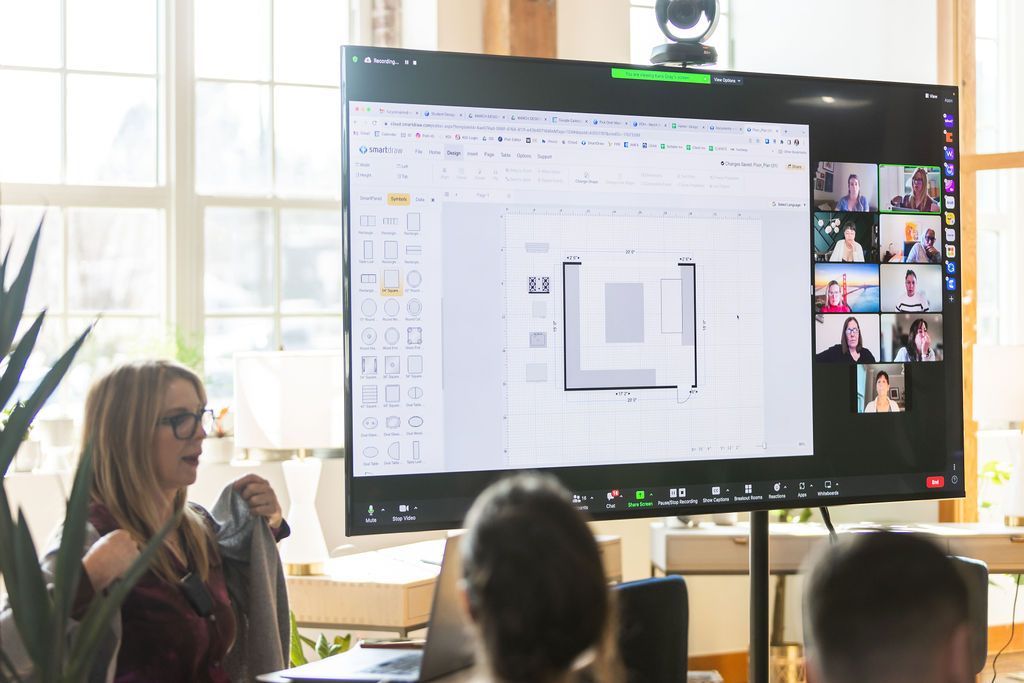 A woman is giving a presentation to a group of people on a large screen.