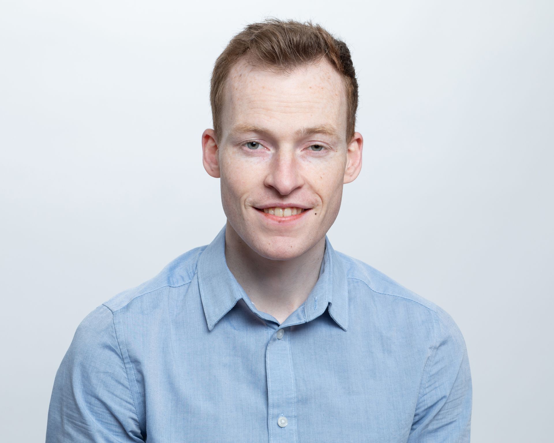 A man in a blue shirt is smiling for the camera.