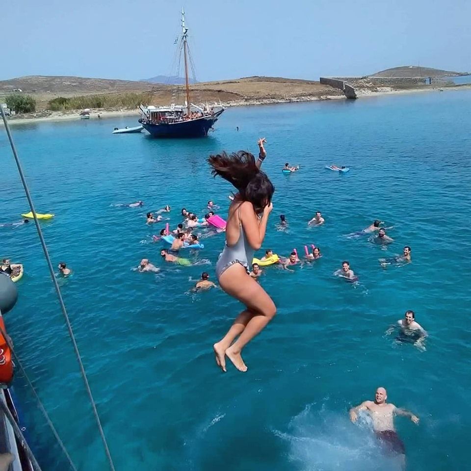 Scenic view of Mykonos beaches with turquoise waters, white sand, and people enjoying a swimming cruise