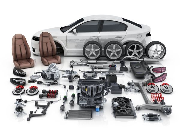 White car disassembled with various parts laid out, including engine, wheels, and seats.