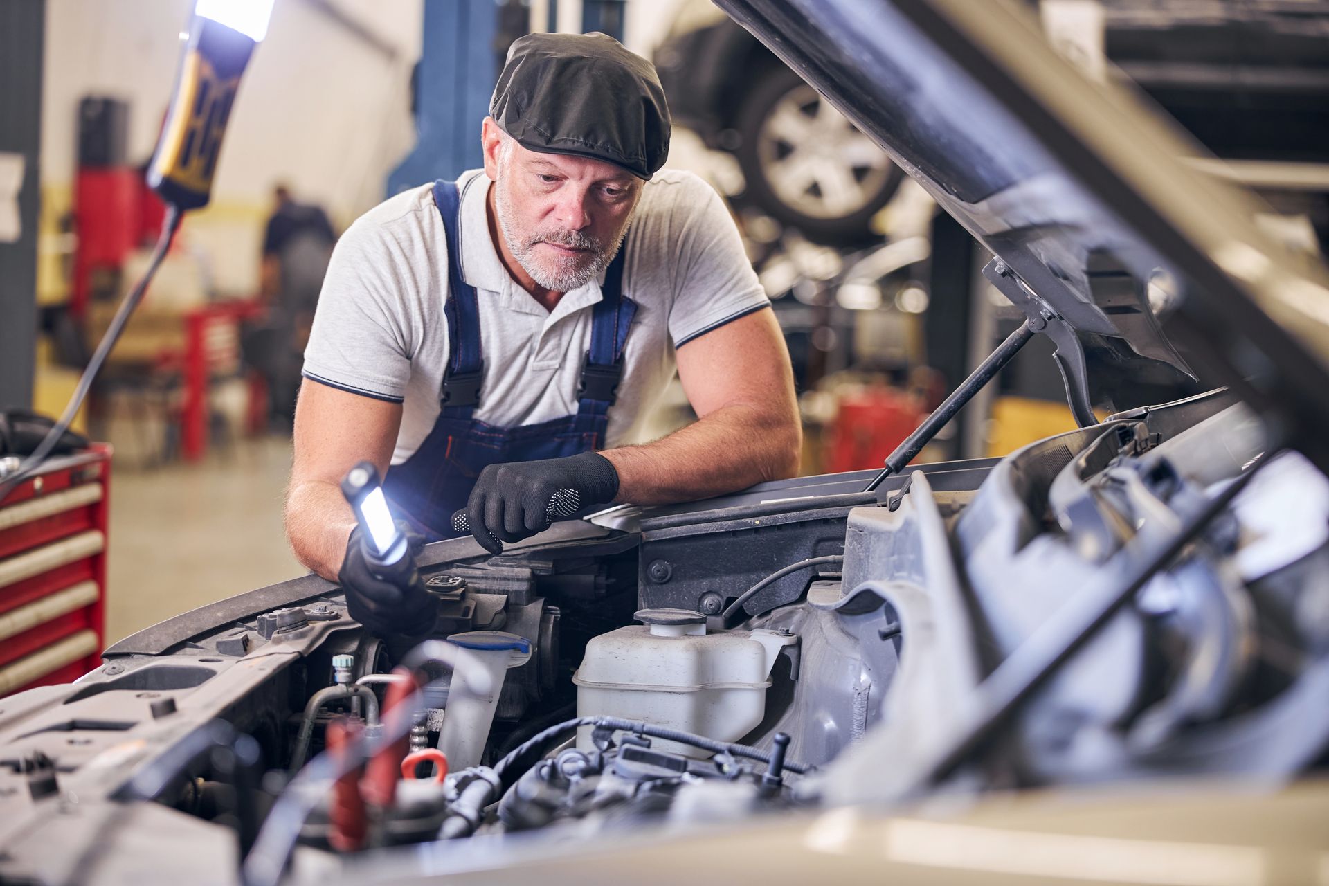 A smiling mechanic working on a car, showcasing automotive servicing skills in a garage setting. A smiling mechanic working on a car, showcasing automotive servicing skills in a garage setting.