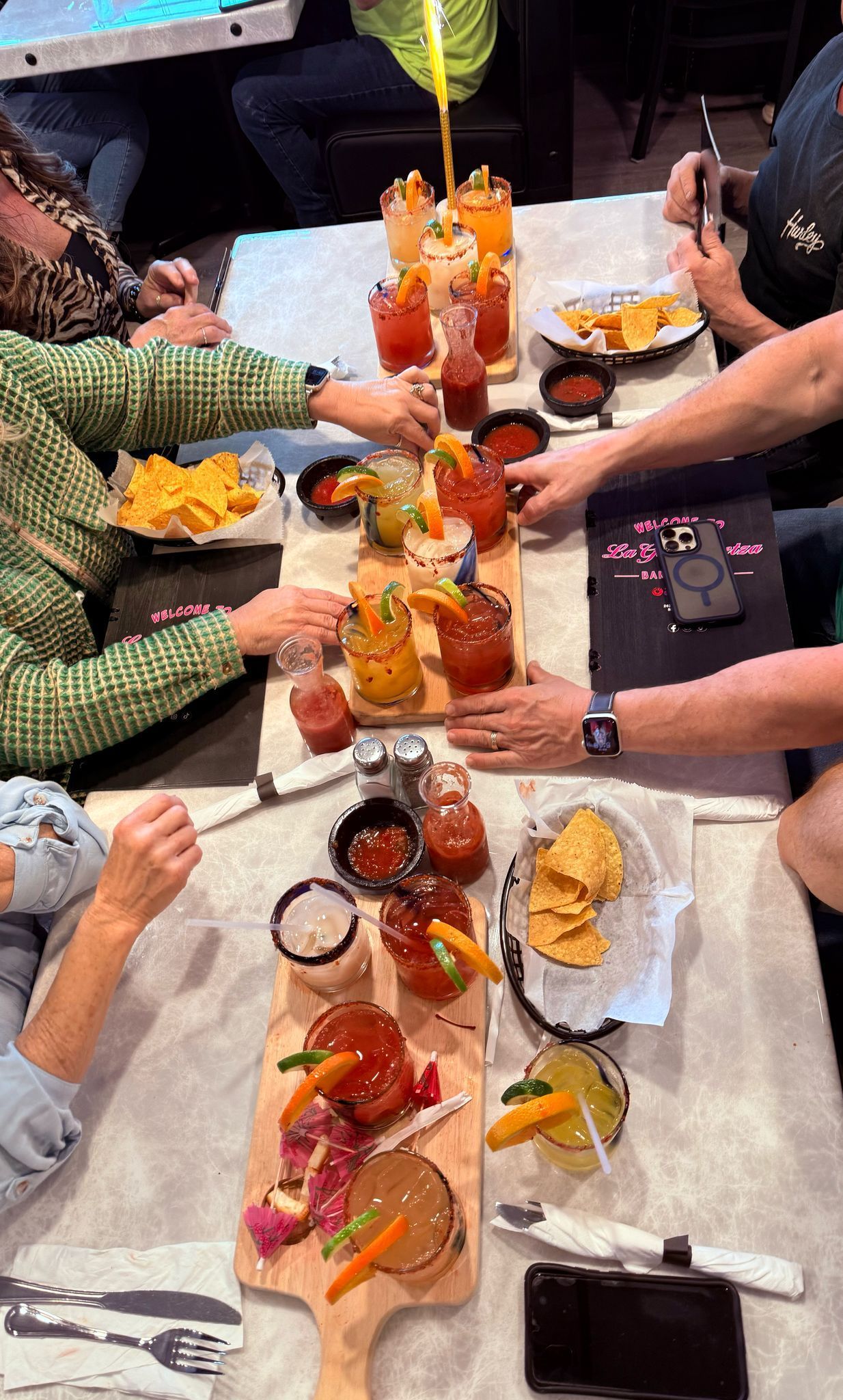 A group of people are sitting at a table with food and drinks.
