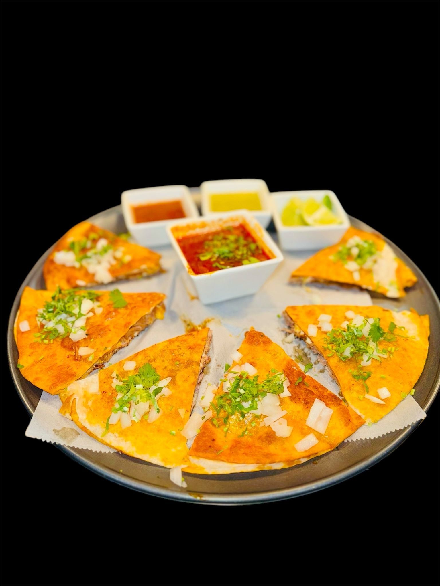 A close up of a plate of food with sauces on a black background.