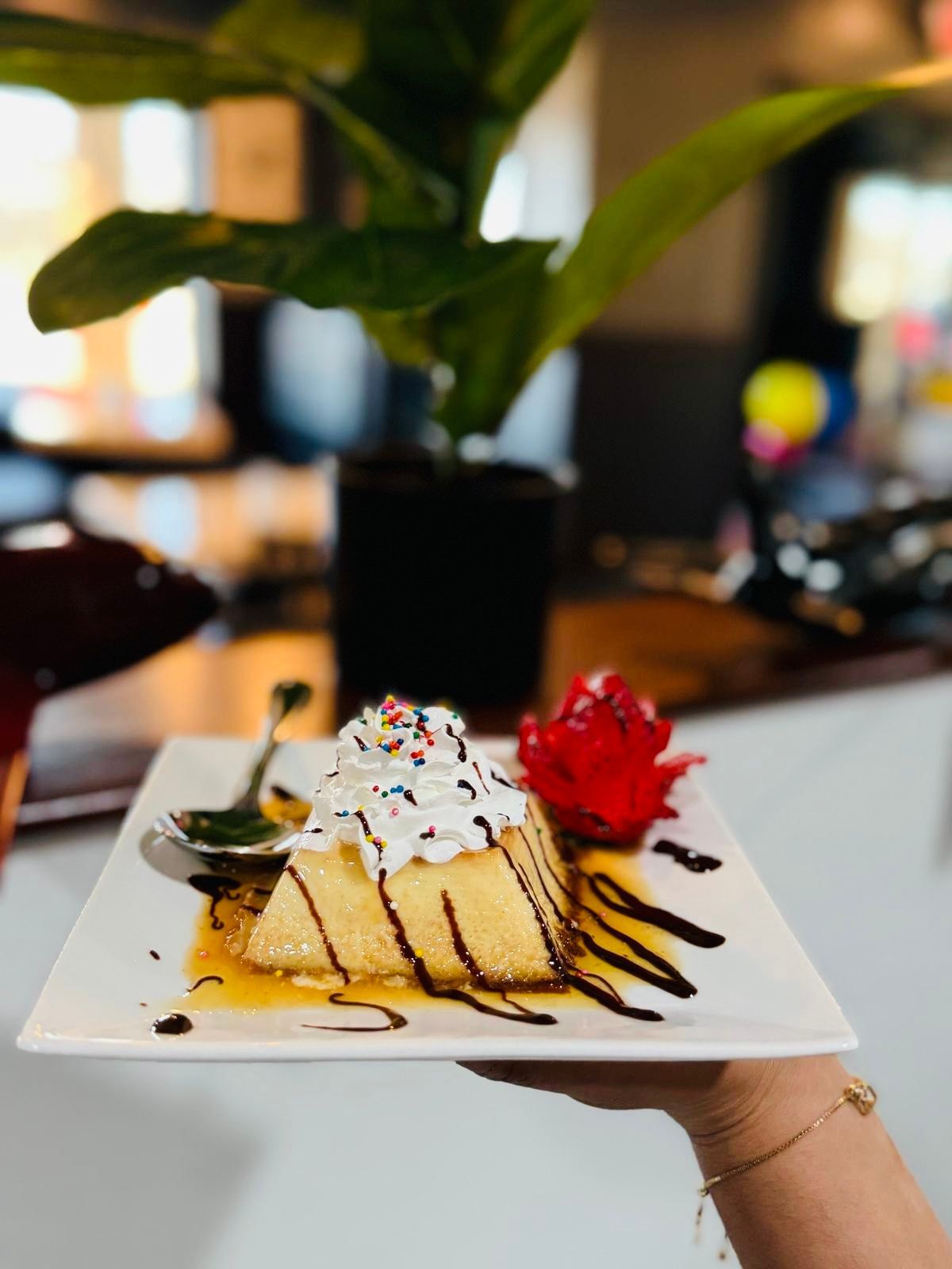 A person is holding a white plate with a piece of cake on it.