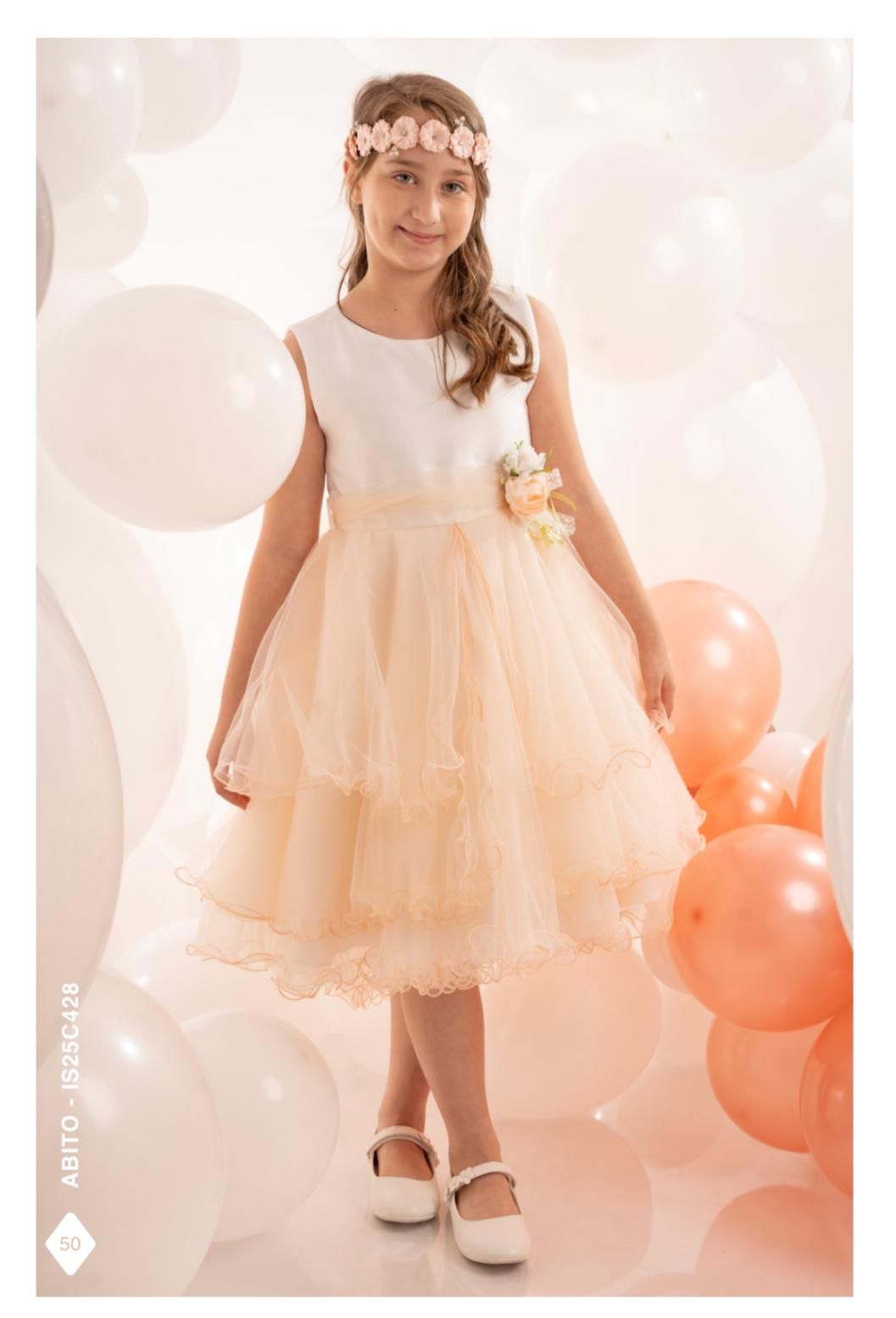 Una ragazza con un vestito color pesca e una fascia floreale posa davanti ai palloncini.