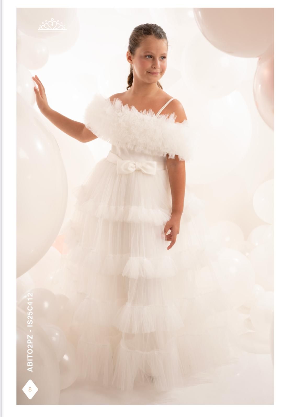 Una ragazza in abito bianco a strati posa vicino ai palloncini.