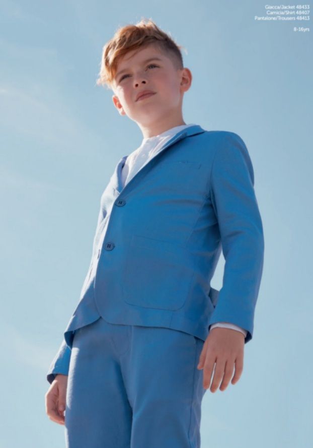 Un ragazzo in abito blu alza lo sguardo e si staglia contro un cielo azzurro brillante.