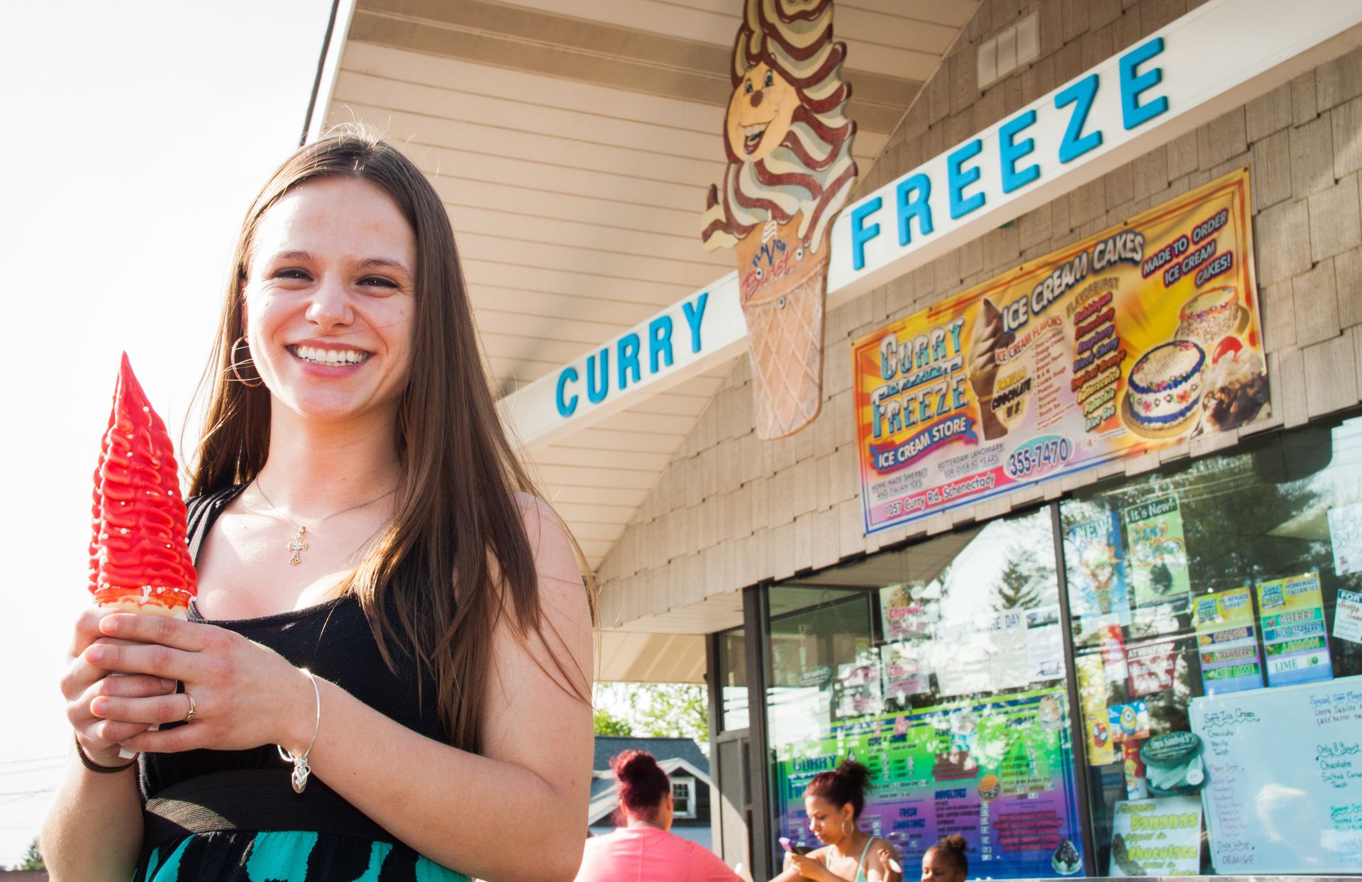 Curry Freeze Ice Cream. person enjoying a cone with cherry dip while standing outside Curry Freeze.
Curry Freeze Ice Cream Shop